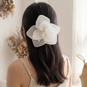 Macro view showing the delicate layers of an oversized white mesh rose flower hair clip.
