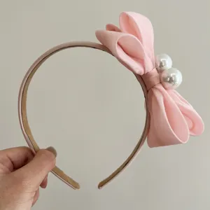 Nahaufnahme eines eleganten rosa Stoffschleifen-Stirnbandes mit Perlenakzenten.