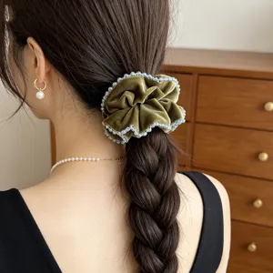 Detailansicht eines olivgrünen Samt-Scrunchies mit funkelnden Kristallkanten am Zopf