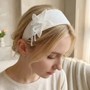 Detail view of a white wide woven headband featuring a handmade beaded flower on model.