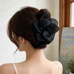 Detail view of a large black mesh rose flower hair clip styled on a classic hair bun.