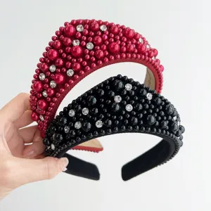 Dettaglio di cerchietti retrò rossi e neri con perle lussuose e strass brillanti.