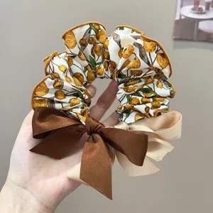 Detailed view of the Korean style hair scrunchie featuring orange fruit prints and bows