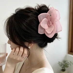 Close-up view of a romantic oversized pink mesh rose flower hair claw clip in a bun.