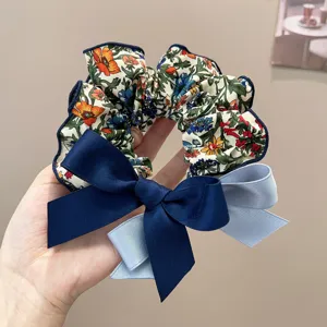 Close-up of a floral scrunchie with navy and light blue bow detail for hair styling.