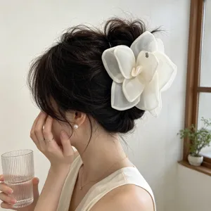 Macro detail of a large white mesh rose flower hair claw clip worn on a bun style