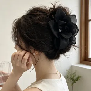 Detailed view of an oversized black gauze rose hair clip worn on a bun.