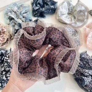 Detail view of a large leopard print scrunchie with elegant pleated ruffle mesh edges.