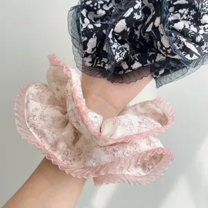 Close-up detail of elegant floral scrunchies with pleated lace edges worn on a wrist