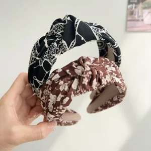 Detailed close-up of wide floral knotted headbands in black and brown patterns