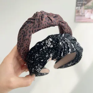 Detailed view showing the knot texture of leopard and floral print wide headbands.