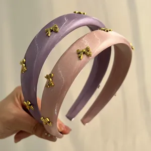 Detail showing satin texture and gold bow charms of pink and purple sponge headbands