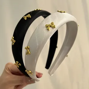 Close-up of black and white satin padded headbands with gold bow details