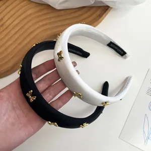 Close-up detail of elegant black and white satin headbands with golden metal butterfly charms
