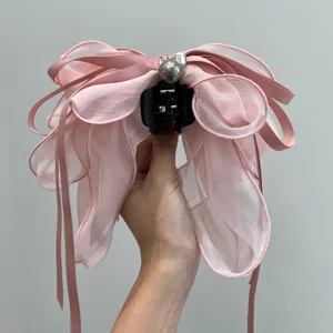 Detalle de la pinza de pelo con lazo de malla rosa, cintas y perlas.