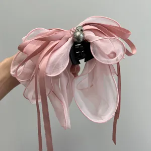 Vista detallada de una pinza para el pelo rosa con lazo de malla y cintas decorativas