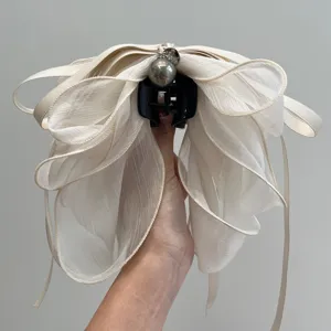 Primer plano de una elegante pinza para el cabello con lazo de malla beige y perla