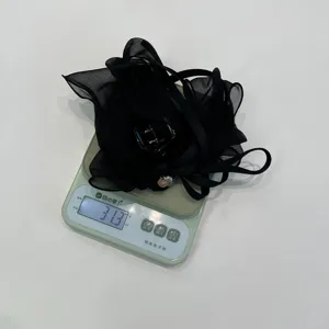Primer plano de pinza de pelo con lazo de malla negra, peso 31,3 g en báscula digital