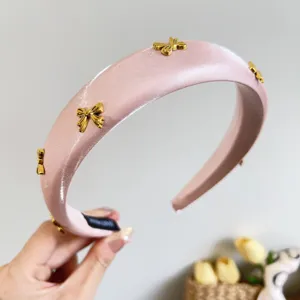 Elegant pink satin padded headband with gold bow charms for high-top hairstyle
