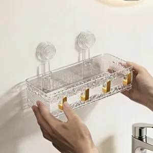 Transparent plastic bathroom suction cup storage rack wall mounted with gold hooks.