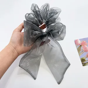 Detailansicht eines schimmernden grauen Organza-Haargummis mit einer großen Schleife