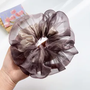 Großaufnahme eines großen Organza-Haargummis in schimmernden Violett- und Champagnertönen