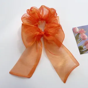 Detailansicht eines lebhaften orangefarbenen Haargummis aus Organza mit Schleife
