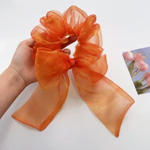 Nahaufnahme des schimmernden orangefarbenen Organza-Schleifen-Haargummis