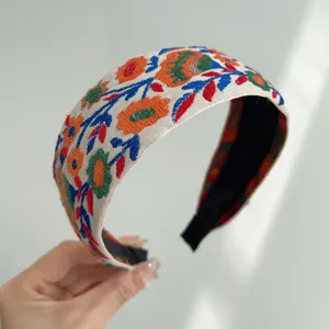 Close-up view of a vintage bohemian floral embroidered wide fabric headband for women
