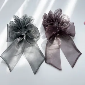 Nahaufnahme von schimmernden Organza-Haargummis mit Schleife in Dunkelgrau und Lila.