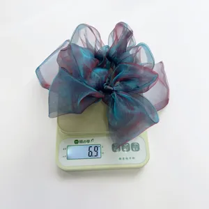 Nahaufnahme eines schimmernden Organza-Haargummis mit Schleife, Gewicht 6,9 g auf Waage