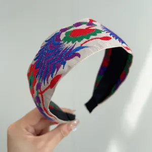 Detail view of a colorful Bohemian style embroidered fabric wide headband for women.