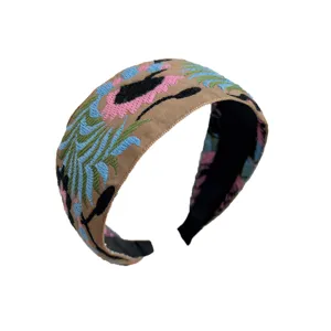 Vintage bohemian wide headband featuring colorful ethnic floral embroidery on beige fabric base.