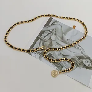 Ceinture chaîne dorée tressée en cuir noir avec pendentif pièce, accessoire élégant pour femmes.
