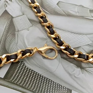 Chaîne entrelacée en métal doré et cuir noir détail, élégante ceinture accessoire de mode.