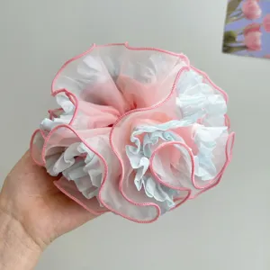 Nahaufnahme eines großen rosa und blauen Organza-Haargummis mit weichen Rüschen