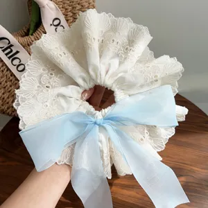 Detail of white double-layer lace scrunchie with light blue organza bow for hair styling.