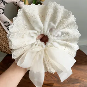 Detailed macro view of the intricate floral lace texture and ivory chiffon bow on the scrunchie