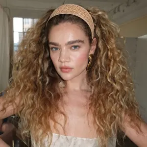 Modèle portant un serre-tête large en paille tressée pour un style vacances chic.