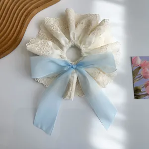Close-up of elegant cream lace scrunchie with a soft light blue ribbon bow detail