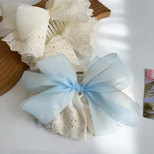 Detailed macro view of an elegant light blue silk ribbon and white floral lace hair claw clip