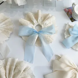 Close-up of elegant double-layer white lace scrunchie with a light blue satin bow detail