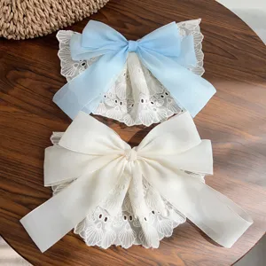 Close-up of oversized double-layered lace bow hair clips in elegant blue and cream white