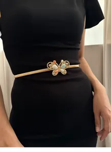 Detail shot of a retro gold butterfly elastic waist belt with colorful stones on a black dress