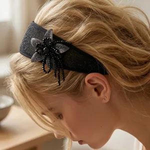 Side detail view of a stylish handmade black wide headband with beaded flower and tassels
