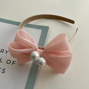 Detailansicht eines eleganten rosa Schleifen-Haarreifs mit dekorativen Perlen