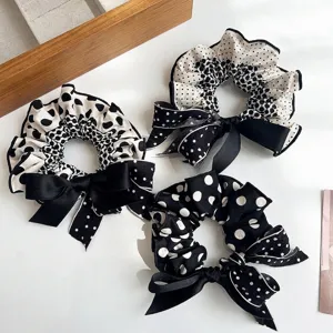 Detailed view of three stylish black and white polka dot scrunchies with elegant bows