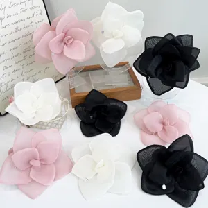 Detail shot of oversized mesh rose flower hair clips in pink, white, and black.