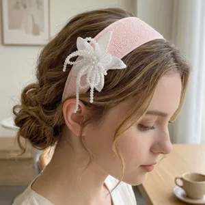 Detailed close-up of handmade beaded white flower on elegant pink fabric headband