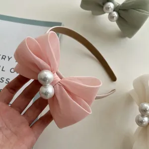Detailansicht eines eleganten rosa Stoffbogen-Haarbandes mit Perlen in der Mitte